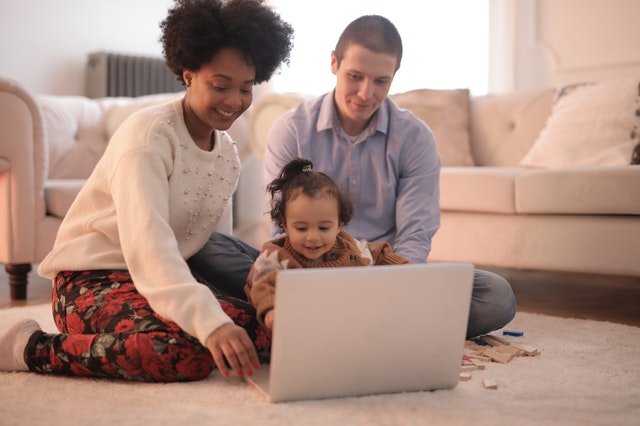 Parents teaching little girl to use a laptop 