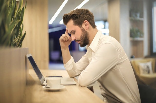 man using laptop and holding head