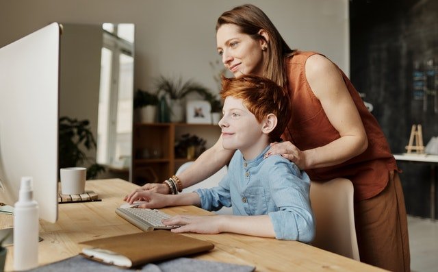 mother guiding son while using pc